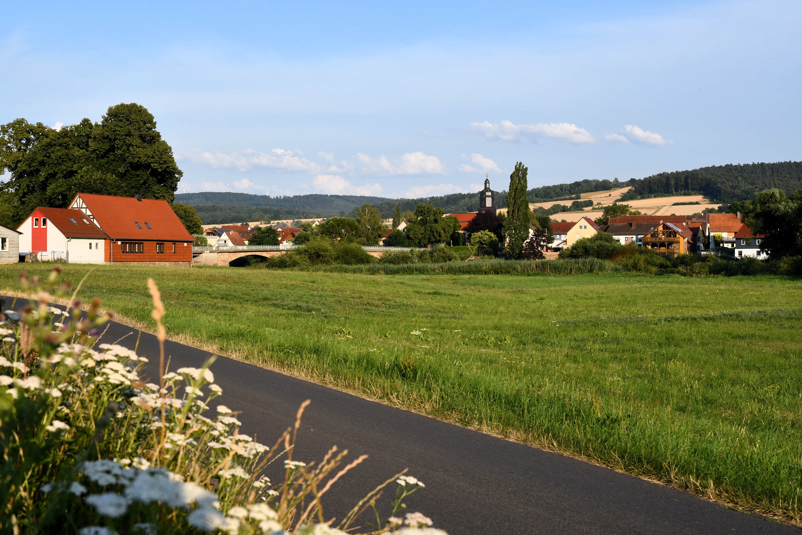Radweg am Fuldaufer mit Blick auf Mecklar und die Kirche
